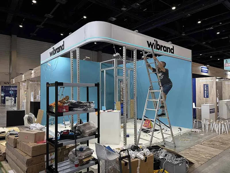 Montage der blauen Wandverkleidung am Wibrand-Messestand während des Innenausbaus